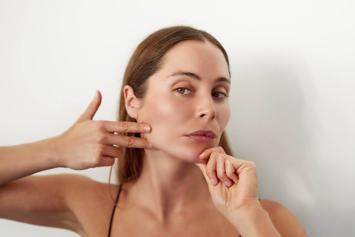 retrato mujer joven caucasica practicando ejercicios de yoga facial en estudio Woman doing face yoga and facial exercises for facial rejuvenation and de-puffing facial contour